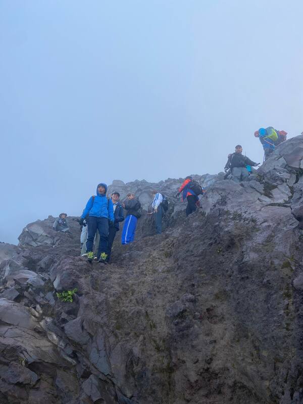 Group Of Hikers Climbing Rocky Misty Mountain Trail