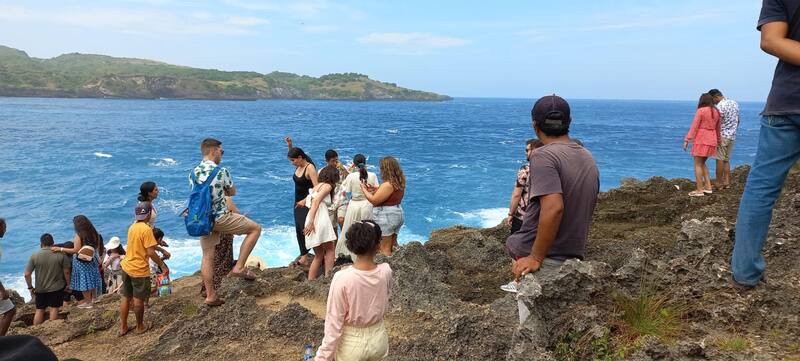 Group Of People Enjoying Ocean View On Rocky Cliff