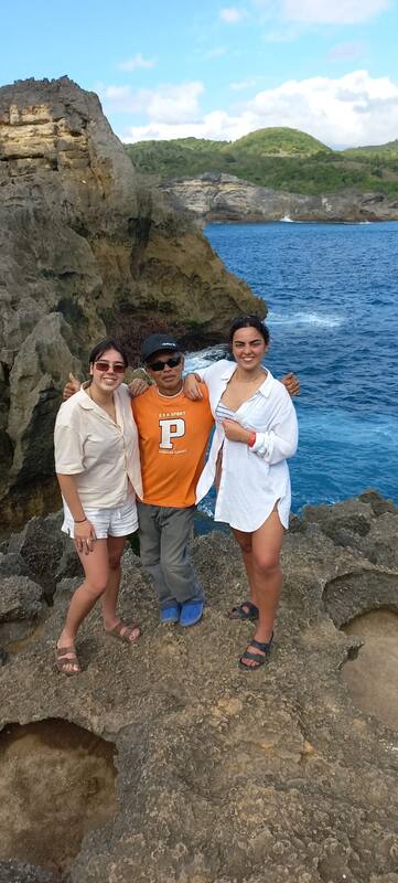 Three People Smiling On Rough Rocky Cliff Near Ocean