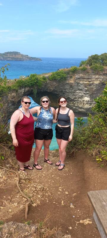 Three Women Tourists Cliffside Ocean View Natural Arch Formation