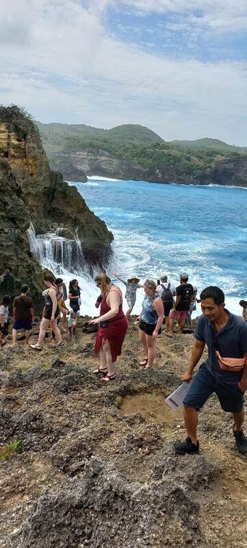 Tourists Visiting Rocky Coast With Waterfall Ocean View