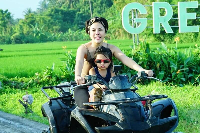 Woman And Child Riding Black Quad Bike Green Fields Background