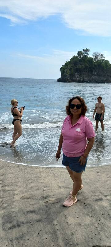 Woman In Pink Shirt On Beach With Two People In Ocean